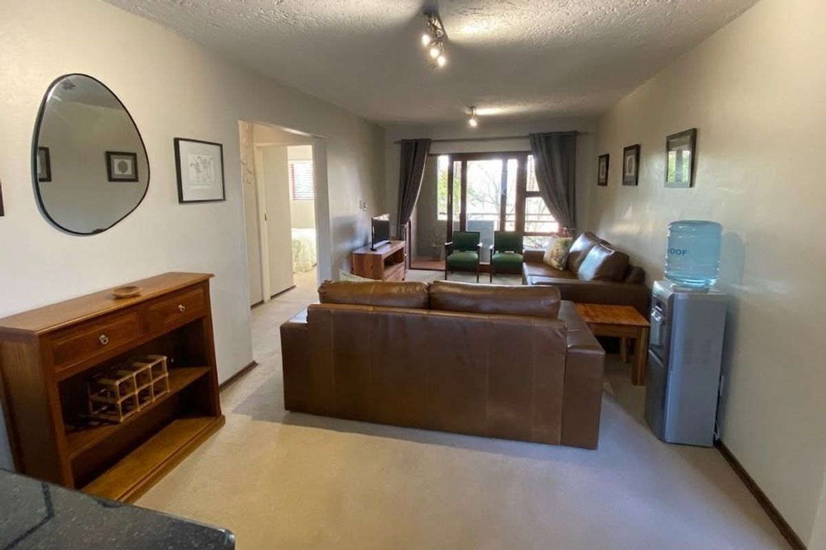 Spacious living room featuring neutral carpeting, ceiling track lighting, and a sliding glass door providing access to an outdoor balcony area.