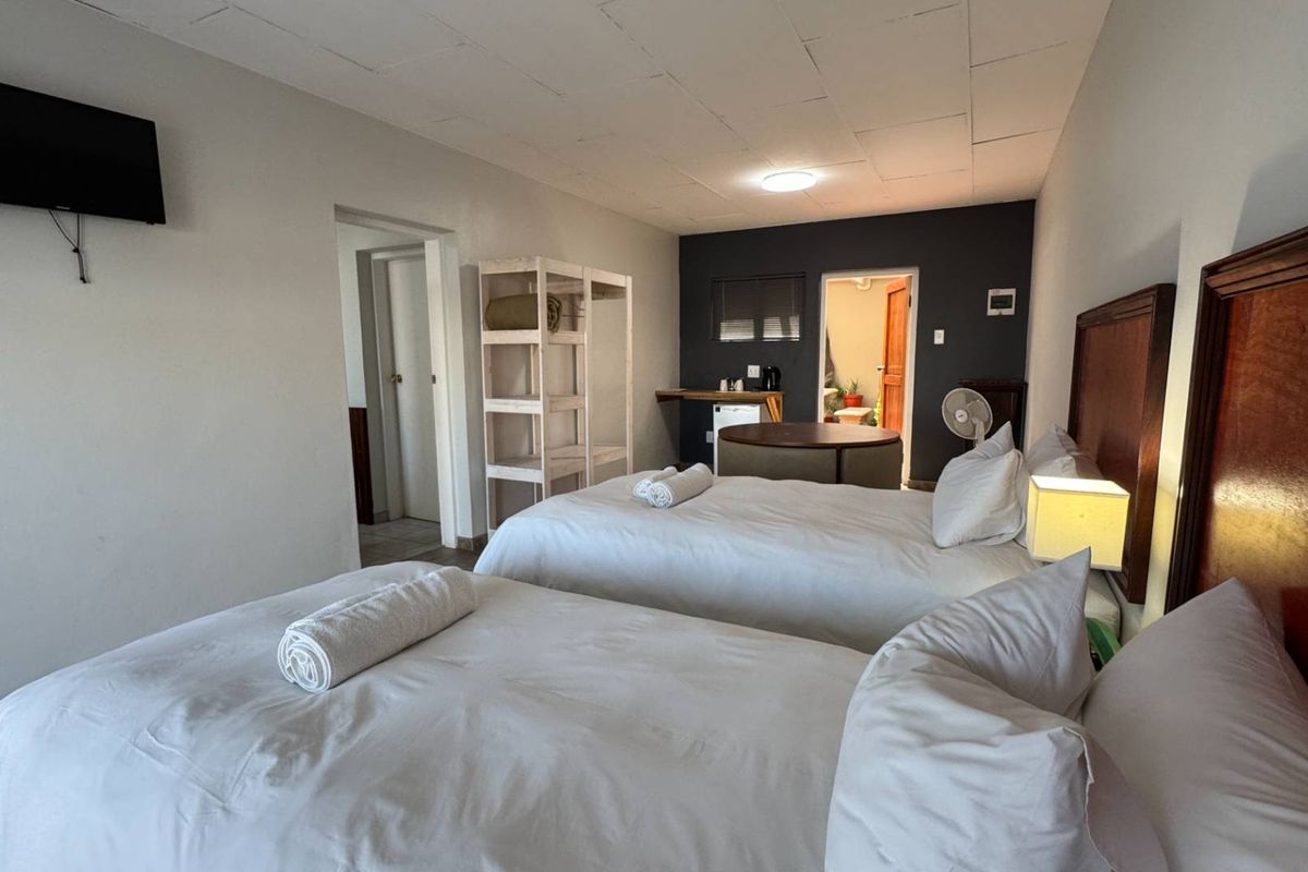 A guest bedroom featuring twin beds, neutral wall tones, and an adjoining bathroom area with basic built-in fixtures.