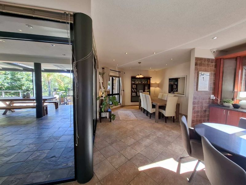 Spacious open-plan living and dining area featuring tiled flooring, recessed lighting, and seamless transition to an outdoor patio through large sliding glass doors.