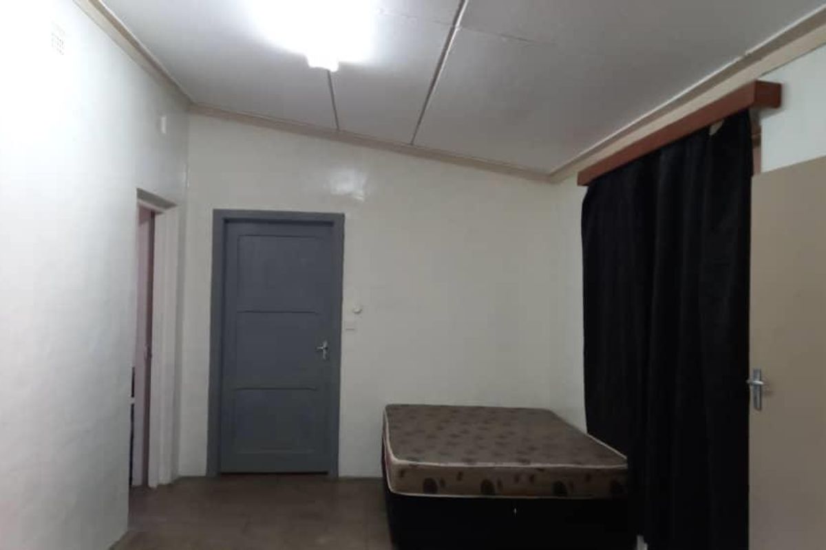 A simple bedroom featuring a single door, tiled flooring, and a basic ceiling structure, offering a functional space ready for updates.