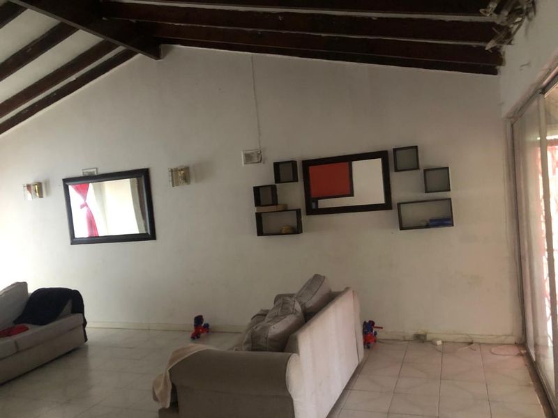 Spacious living area featuring exposed timber ceiling beams, tiled flooring, and large sliding glass doors providing access to the exterior.