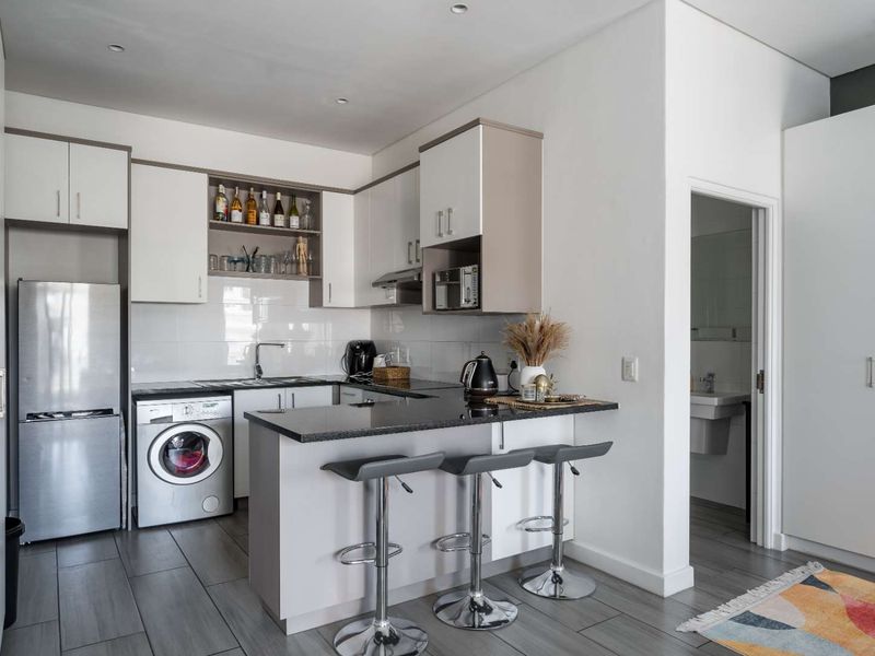 Modern open-plan kitchen featuring granite countertops, built-in cabinetry, and integrated laundry facilities, seamlessly connected to the living area.