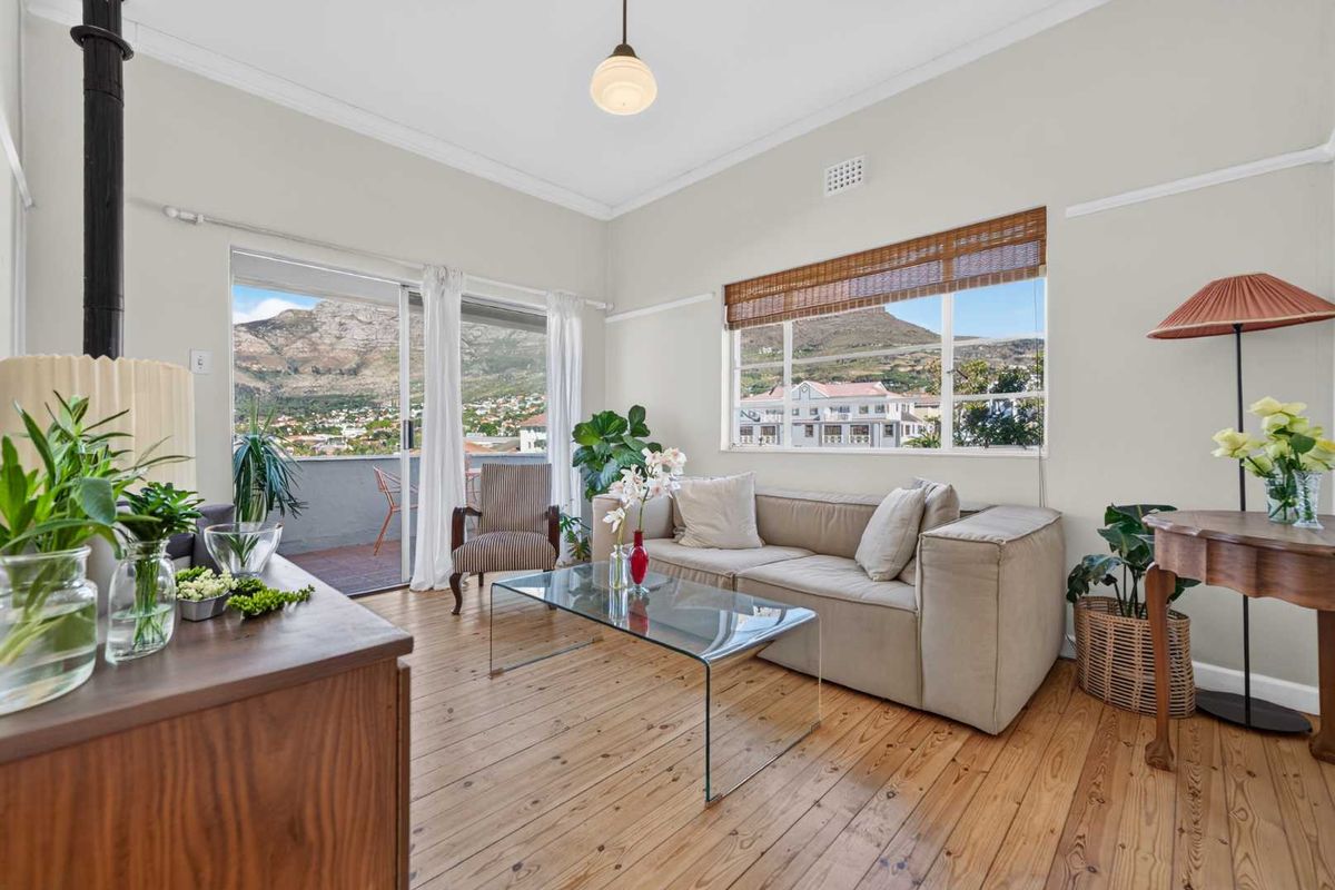 Bright living room featuring original hardwood flooring, large windows with mountain views, and direct access to a private balcony.
