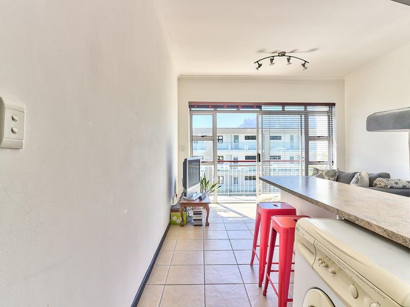 Open plan living area featuring tiled flooring, a breakfast bar, and a sliding glass door leading to a balcony with natural light.
