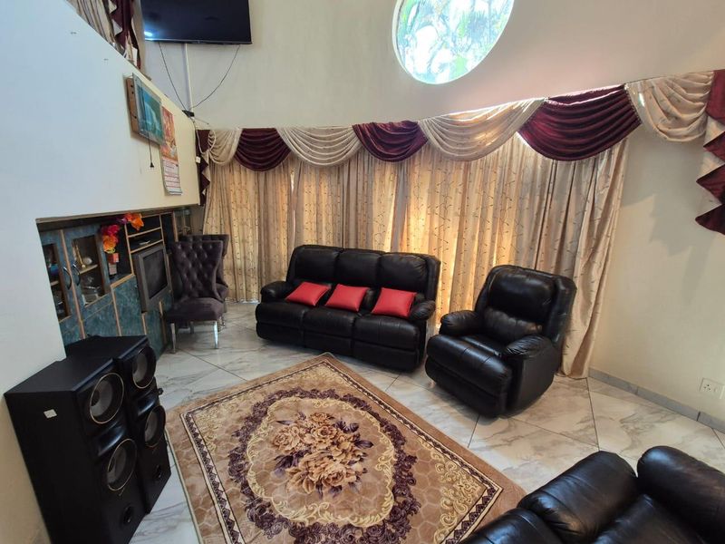 A living room featuring tiled flooring, built-in cabinetry, and a distinctive circular window, offering a spacious area with high ceilings.