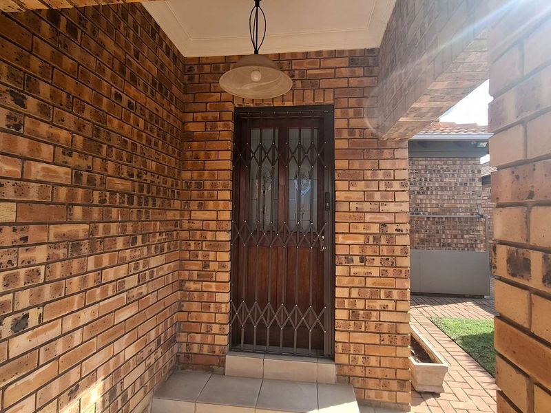 A covered entrance area featuring face brick walls, a secure metal gate, and tiled flooring, providing a solid and welcoming entry point.