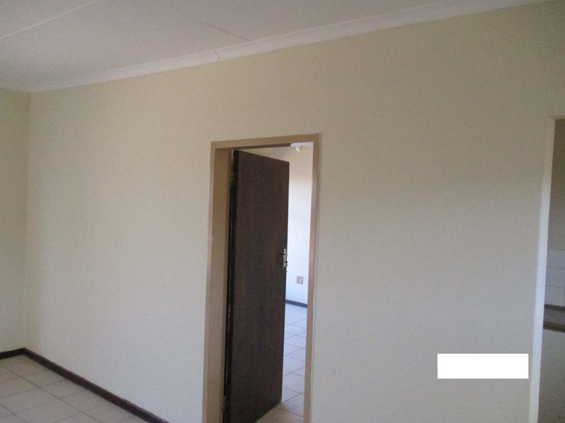 An empty living area featuring neutral walls, tiled flooring, and coved ceilings, providing a blank canvas for interior design.