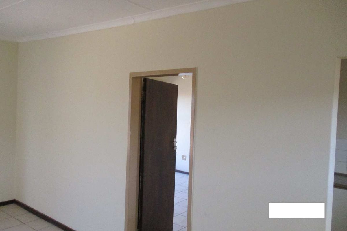 An empty living area featuring neutral walls, tiled flooring, and coved ceilings, providing a blank canvas for interior design.