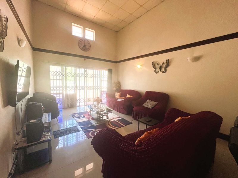 Spacious living room featuring high ceilings, tiled flooring, and large sliding doors with security gates leading to the exterior.