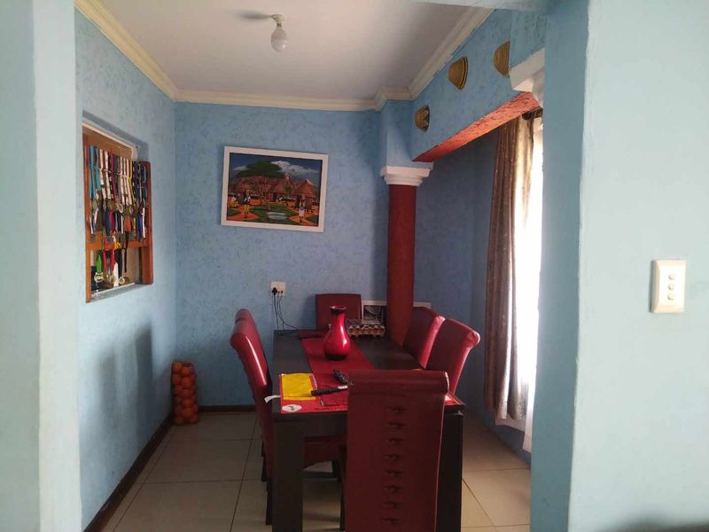 A dining room featuring tiled flooring, a decorative column, and coved ceiling details, offering a functional space for family meals.