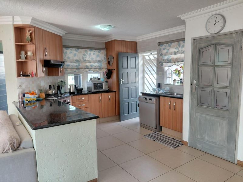Functional kitchen featuring wood-finish cabinetry, granite countertops, built-in cooking appliances, and tiled flooring with direct access to the exterior.