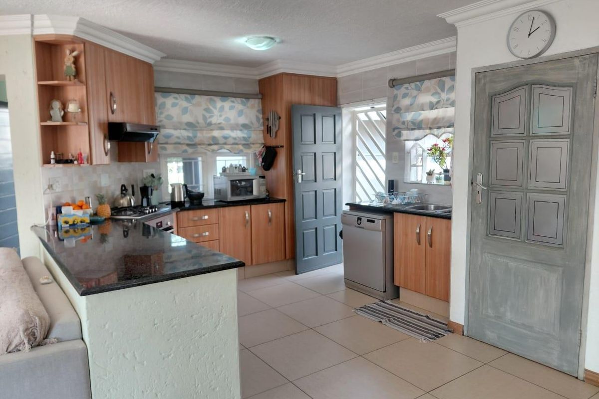 Functional kitchen featuring wood-finish cabinetry, granite countertops, built-in cooking appliances, and tiled flooring with direct access to the exterior.