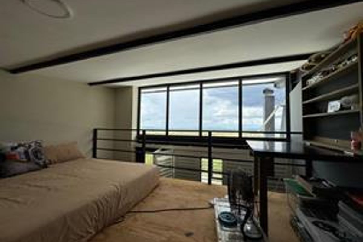 A loft-style bedroom featuring exposed structural beams, large windows with landscape views, and a mezzanine-level layout.