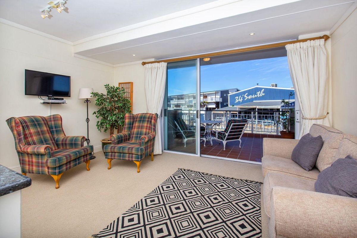 A comfortable living room featuring neutral carpeting, recessed lighting, and a large sliding glass door providing access to an outdoor balcony area.