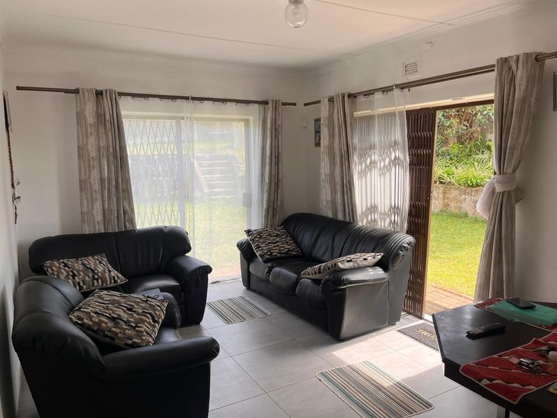 Bright living room featuring neutral tiled flooring and dual sliding glass doors providing direct access to the rear garden area.
