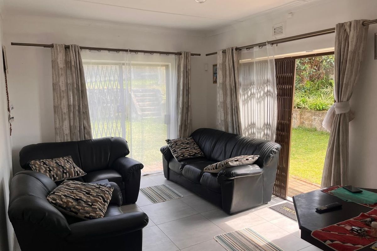 Bright living room featuring neutral tiled flooring and dual sliding glass doors providing direct access to the rear garden area.