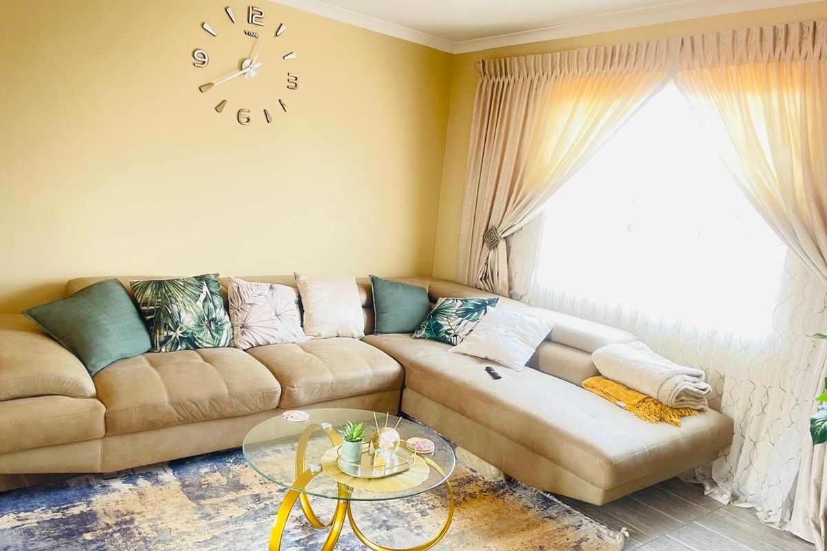 A comfortable living room featuring tiled flooring, large window with curtains, and neutral wall finishes.