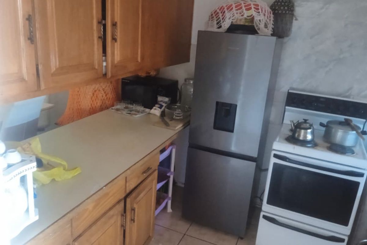 A functional kitchen featuring wooden cabinetry, tiled flooring, and a freestanding stove, offering a practical layout for daily meal preparation.