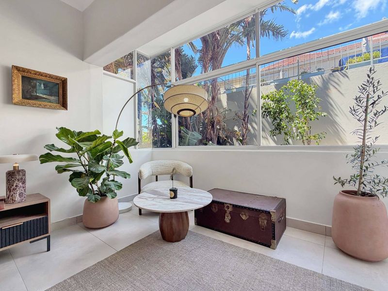 Bright living area featuring expansive floor-to-ceiling windows that provide abundant natural light and views of the surrounding greenery.