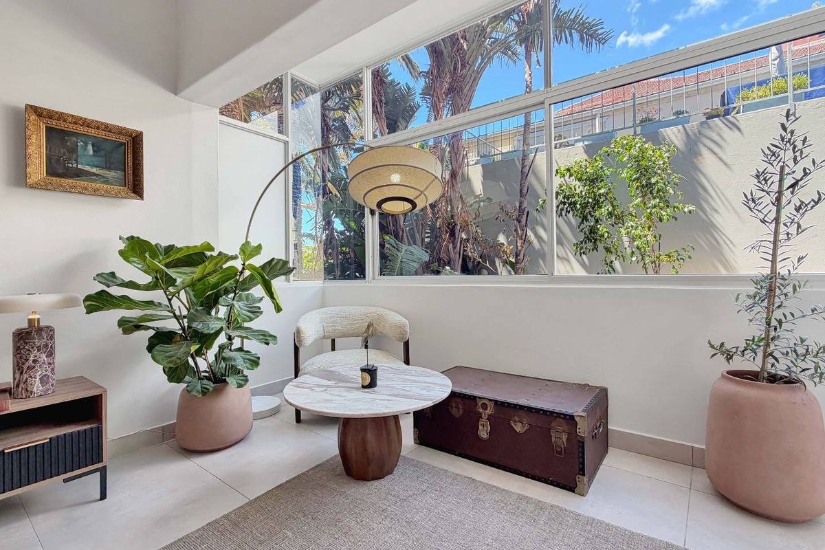 Bright living area featuring expansive floor-to-ceiling windows that provide abundant natural light and views of the surrounding greenery.