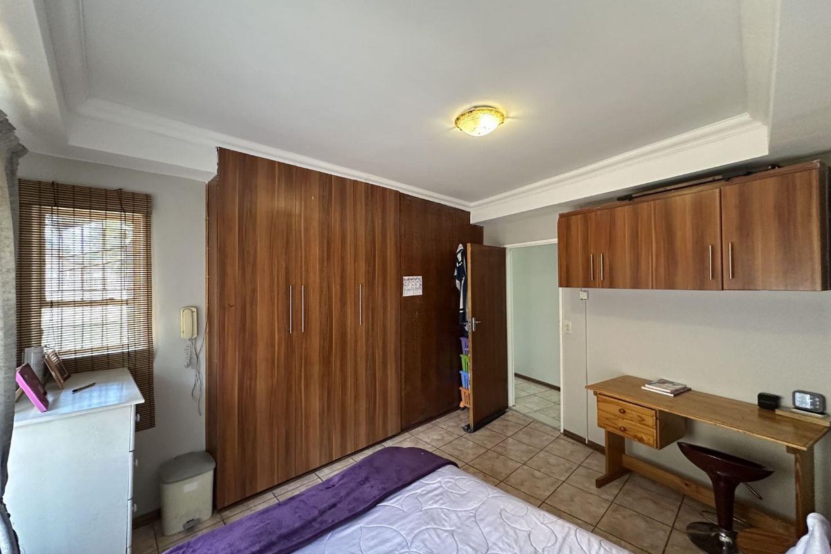 A functional bedroom featuring extensive built-in wooden cabinetry, tiled flooring, and a ceiling-mounted light fixture.