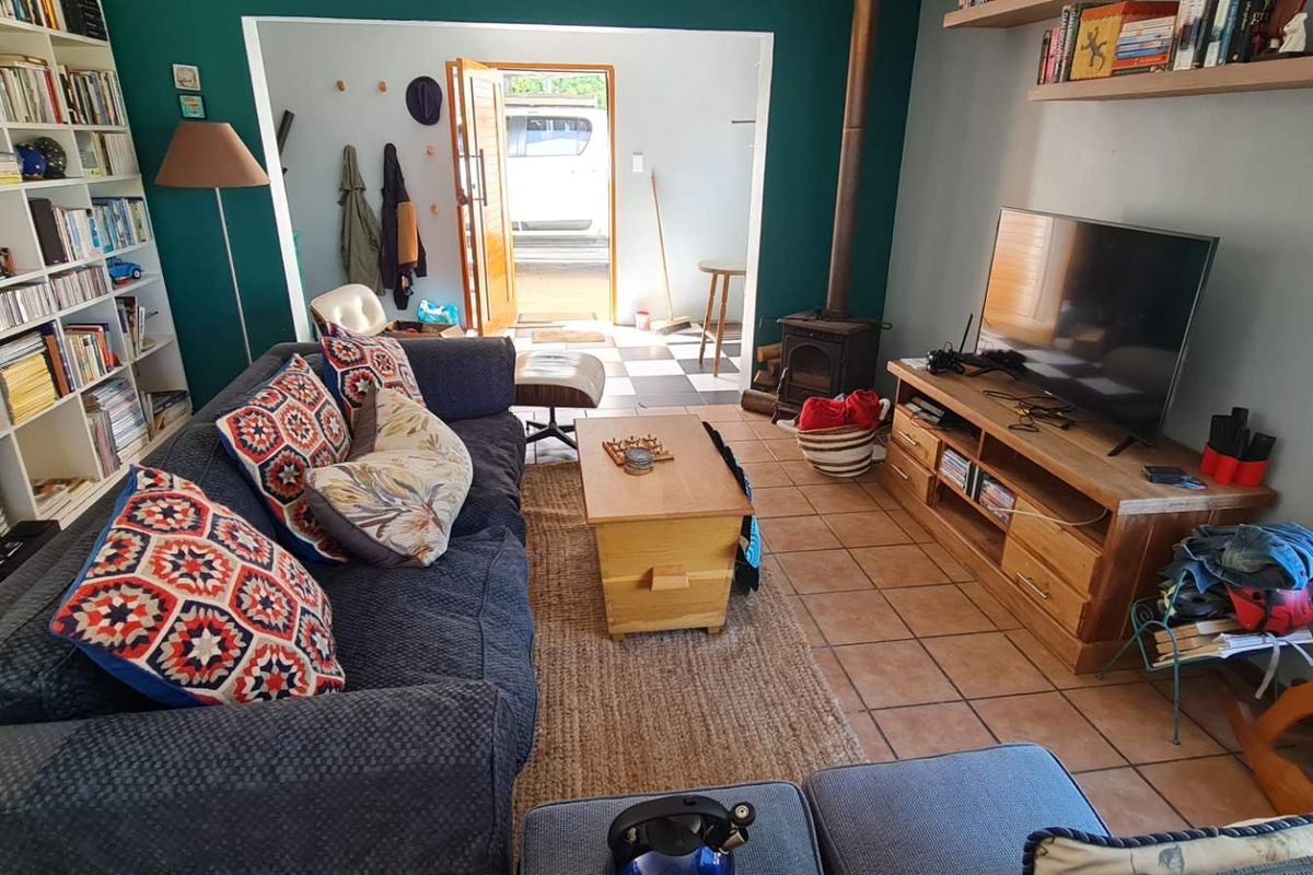 A cozy living room featuring built-in shelving, a wood-burning stove, and tiled flooring, with an open transition to an adjacent entry area.