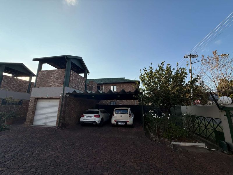 Front exterior view of the apartment complex featuring a face brick facade, a covered carport, and a paved driveway.