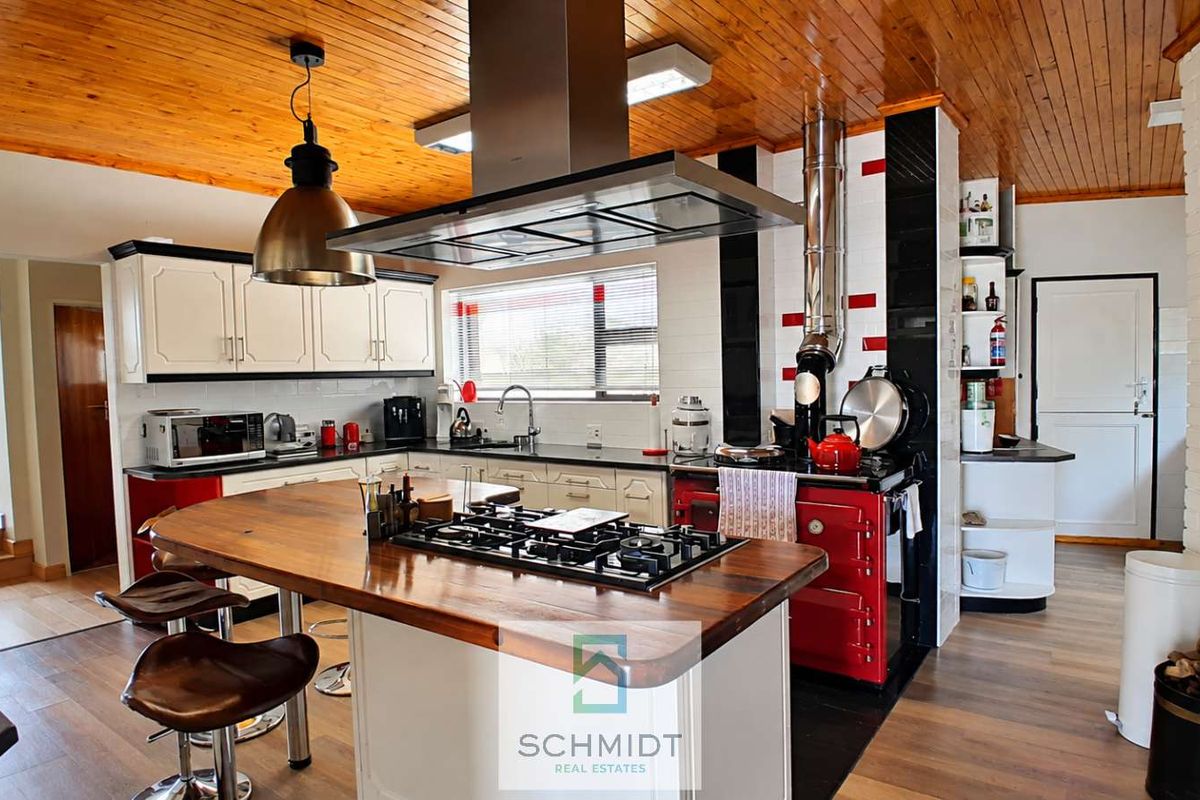Spacious kitchen featuring a central island with a gas hob, timber ceiling, and ample built-in cabinetry with a modern aesthetic.