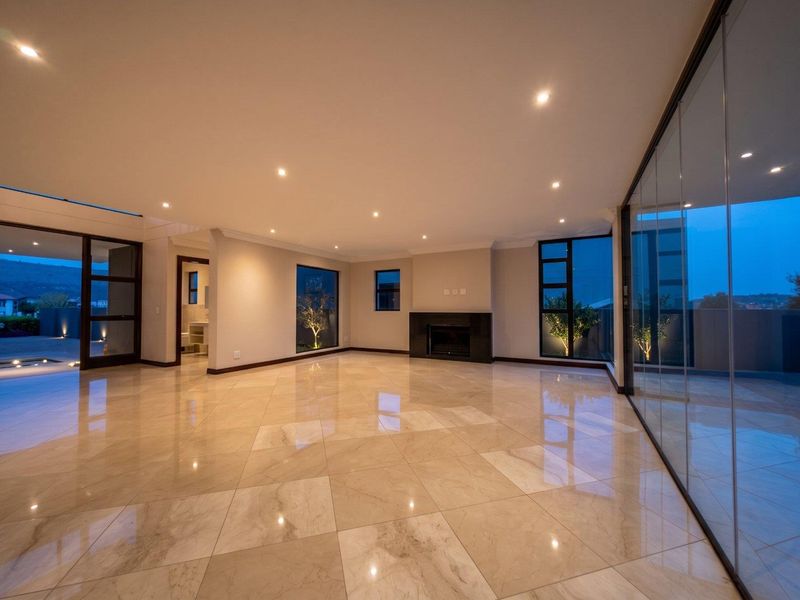 Spacious, modern open-plan living area featuring polished tile flooring, recessed lighting, a built-in fireplace, and expansive glass doors leading to an outdoor space.