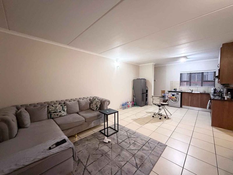 Open plan living area featuring tiled flooring and a functional kitchen with granite countertops and built-in cabinetry.
