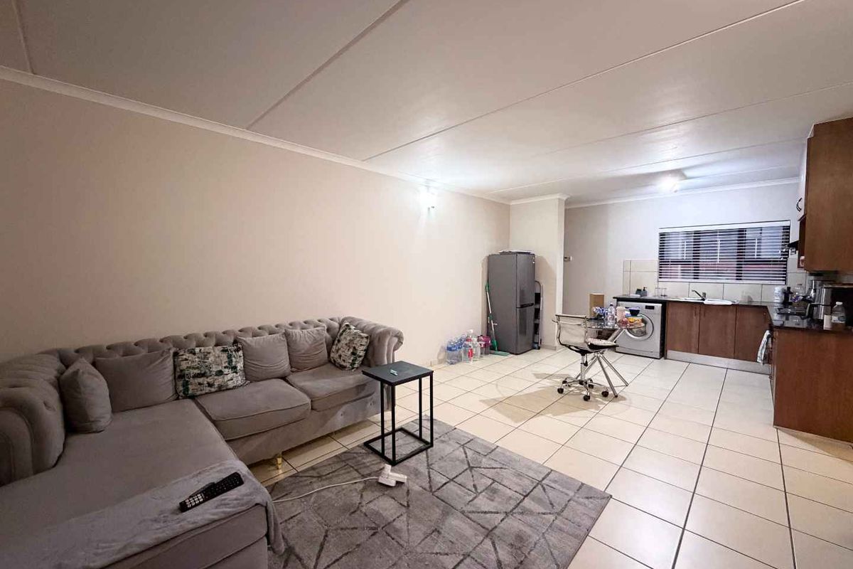 Open plan living area featuring tiled flooring and a functional kitchen with granite countertops and built-in cabinetry.