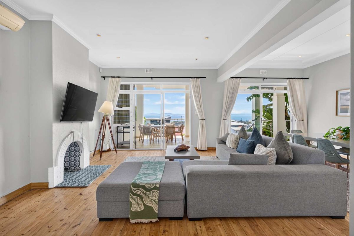 Spacious living room featuring hardwood floors, a decorative fireplace, and large sliding glass doors that open to a balcony with scenic views.