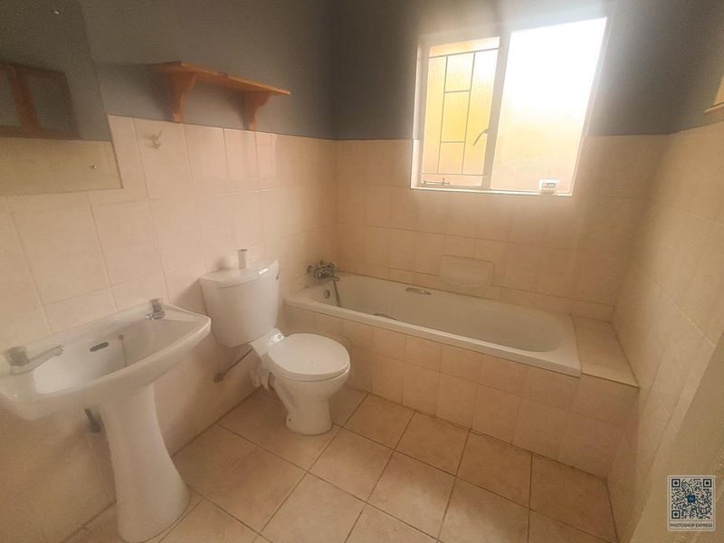 A dated bathroom featuring a pedestal basin, toilet, and built-in bathtub with tiled finishes, requiring modernization to improve its overall condition and appeal.