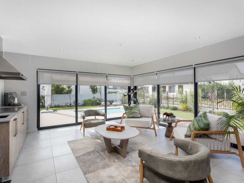 Modern open-plan living area featuring a sleek kitchen, tiled floors, and expansive sliding glass doors providing seamless access to the outdoor pool and garden.