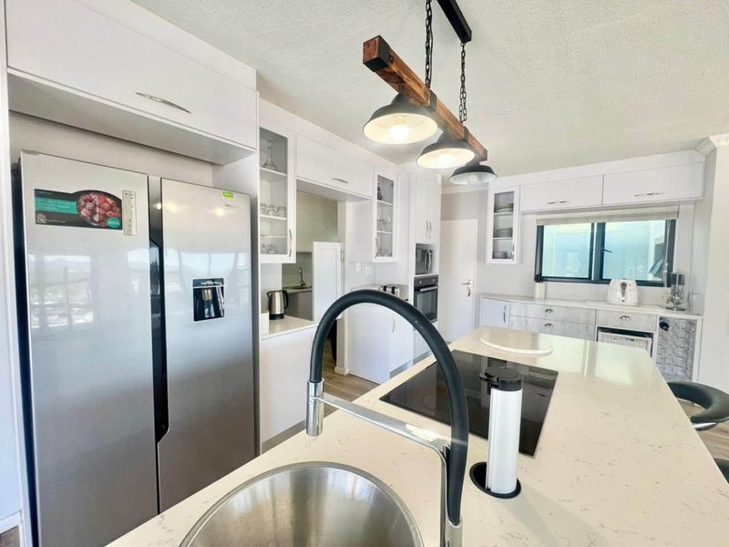 Modern kitchen featuring a central island with quartz countertops, induction cooktop, integrated appliances, and stylish pendant lighting.