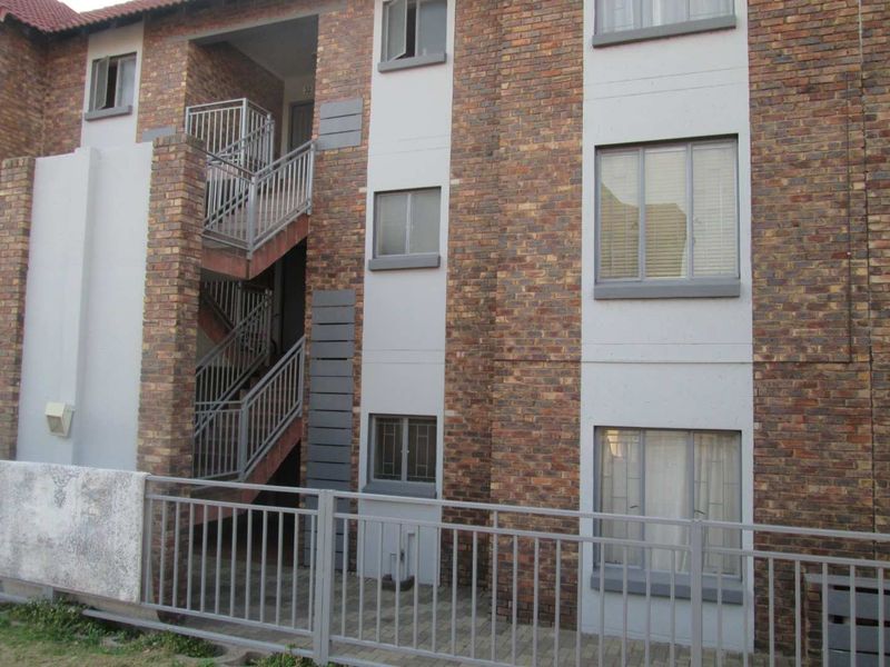 Exterior view of an apartment building featuring a face brick facade, metal staircase, and secure aluminium window frames.