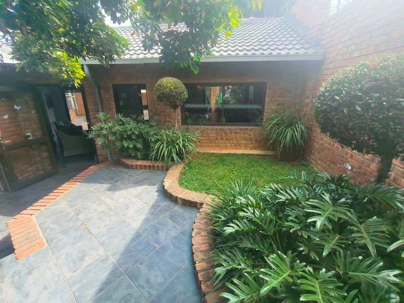 A private rear courtyard featuring a slate-tiled patio, brick garden borders, and established landscaping, providing a peaceful outdoor living space.