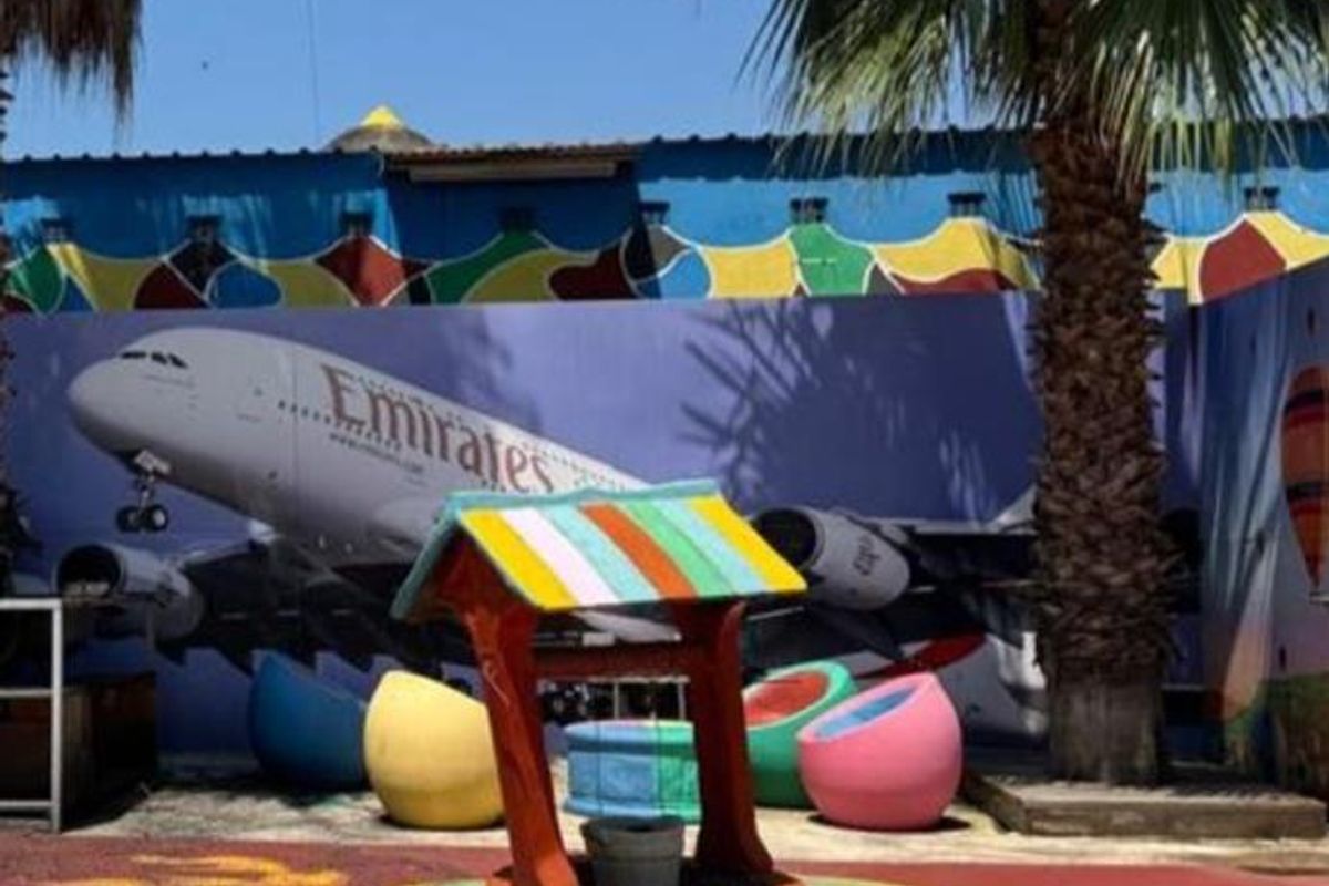 Outdoor courtyard area featuring a decorative wishing well, palm trees, and a large mural on the boundary wall.