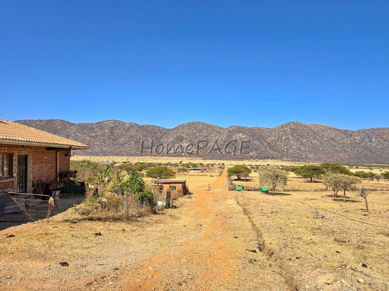 Expansive rural landscape view featuring a dirt track, natural vegetation, and scenic mountain backdrop on a small holding property.