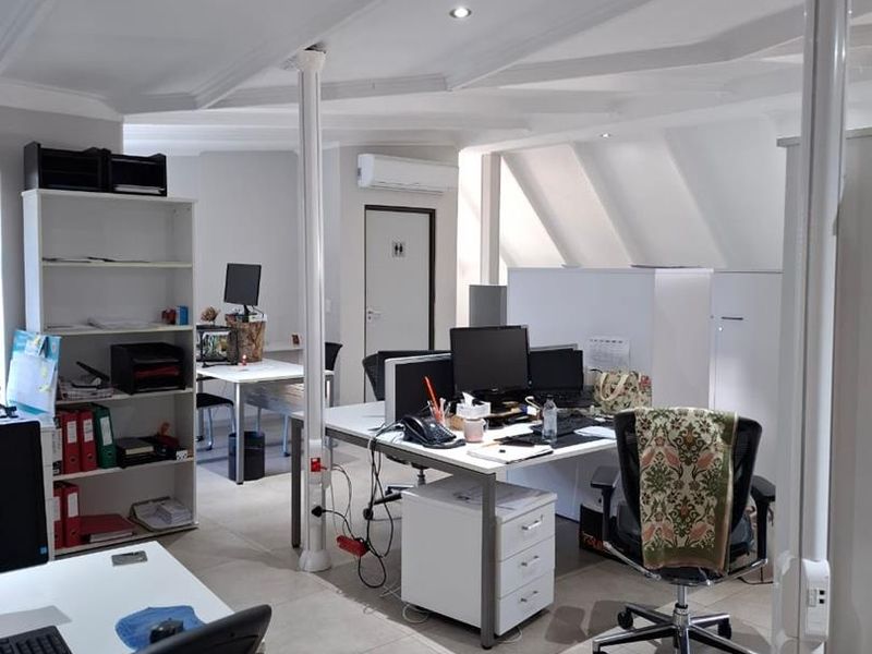 A functional open-plan office space featuring tiled flooring, recessed lighting, and integrated air conditioning, providing a clean and professional work environment.