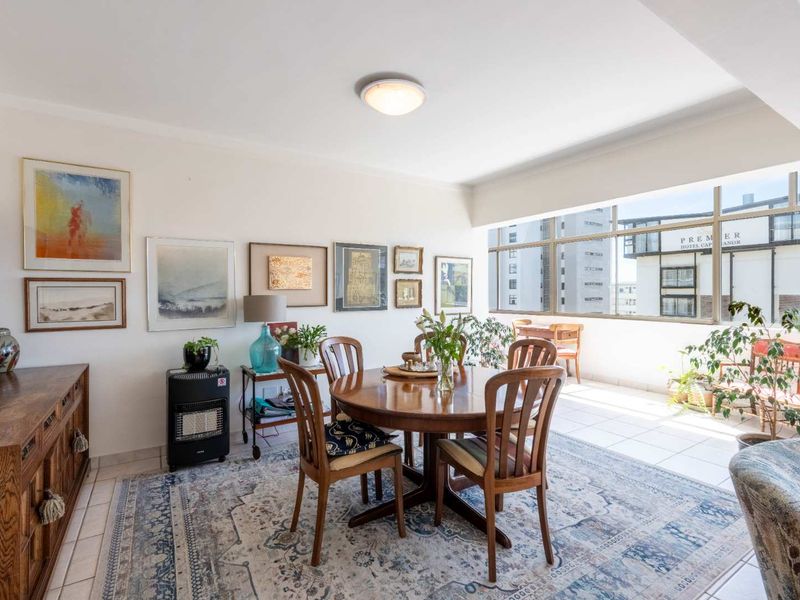 Bright open-plan living and dining area featuring tiled flooring and large windows that provide ample natural light and an urban view.