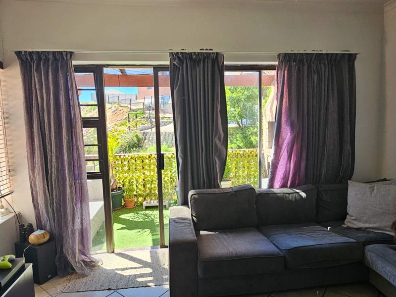 A living room featuring tiled flooring and large sliding glass doors that provide direct access to an outdoor patio area.