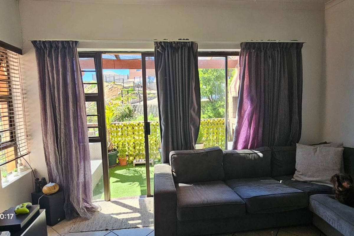 A living room featuring tiled flooring and large sliding glass doors that provide direct access to an outdoor patio area.