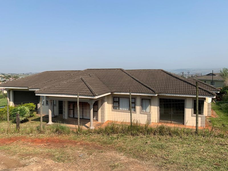 A single-story residential property featuring a tiled roof, covered patio with columns, and an integrated garage, set on a large plot.