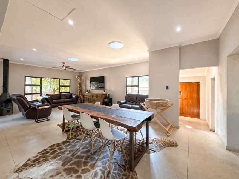 Spacious open-plan living and dining area featuring tiled floors, a freestanding fireplace, skylights, and large windows providing ample natural light.