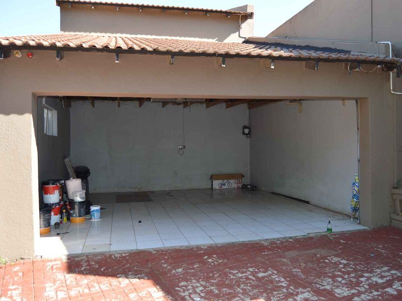 An open-plan garage space featuring tiled flooring and exposed timber rafters, requiring some maintenance and finishing to the roof structure and driveway.