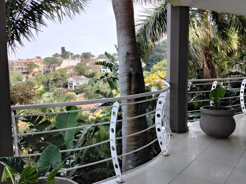 Spacious covered balcony featuring tiled flooring, a modern metal balustrade, and scenic views of the surrounding neighborhood.