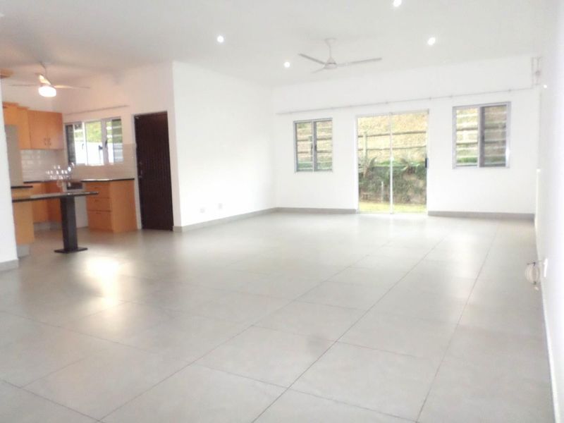 Spacious open-plan living area featuring tiled floors, recessed lighting, ceiling fans, and an adjoining kitchen with built-in cabinetry and island.