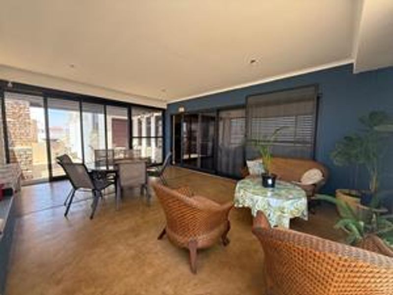 A spacious covered patio featuring polished concrete floors, recessed lighting, and large sliding glass doors that provide seamless indoor-outdoor flow.