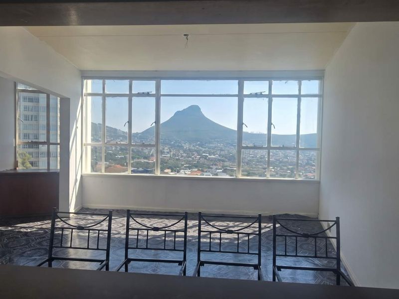 An empty living area featuring large windows that frame a prominent mountain view, offering a blank canvas for renovation and interior design.